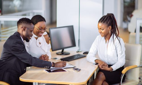 african couple getting car key from car dealer in showroom and signing contract